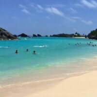 Bañistas en East Whale Bay, una playa pública de arena rosada en Bermudas, de aguas turquesa.