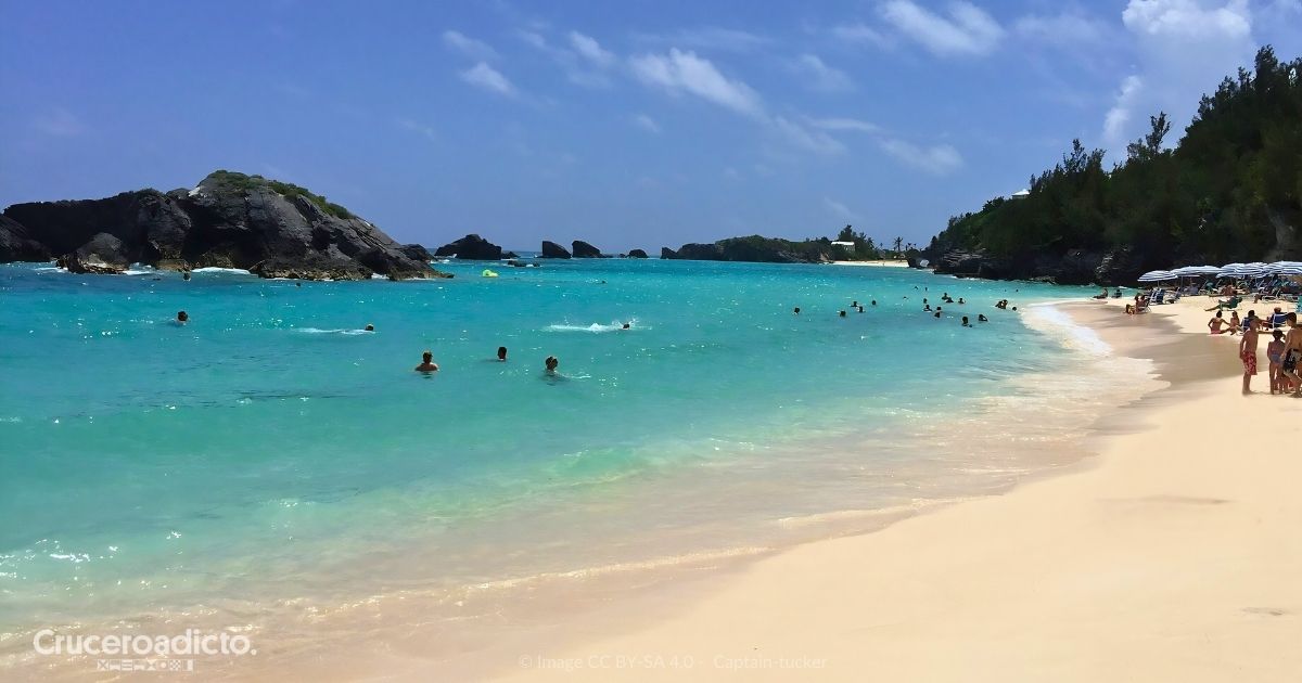 Bañistas en East Whale Bay, una playa pública de arena rosada en Bermudas, de aguas turquesa.
