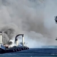 El nuevo muelle de cruceros de Whittier, en Alaska, envuelto en una densa humareda durante el incendio, con un crucero de Norwegian Cruise Line atracado al lado y la costa montañosa al fondo. Imagen cortesía del Girdwood Fire Department.