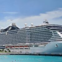 El MSC Seaside, de MSC Cruceros, atracado junto a la playa de Ocean Cay, con bañistas en el agua turquesa en primer término.