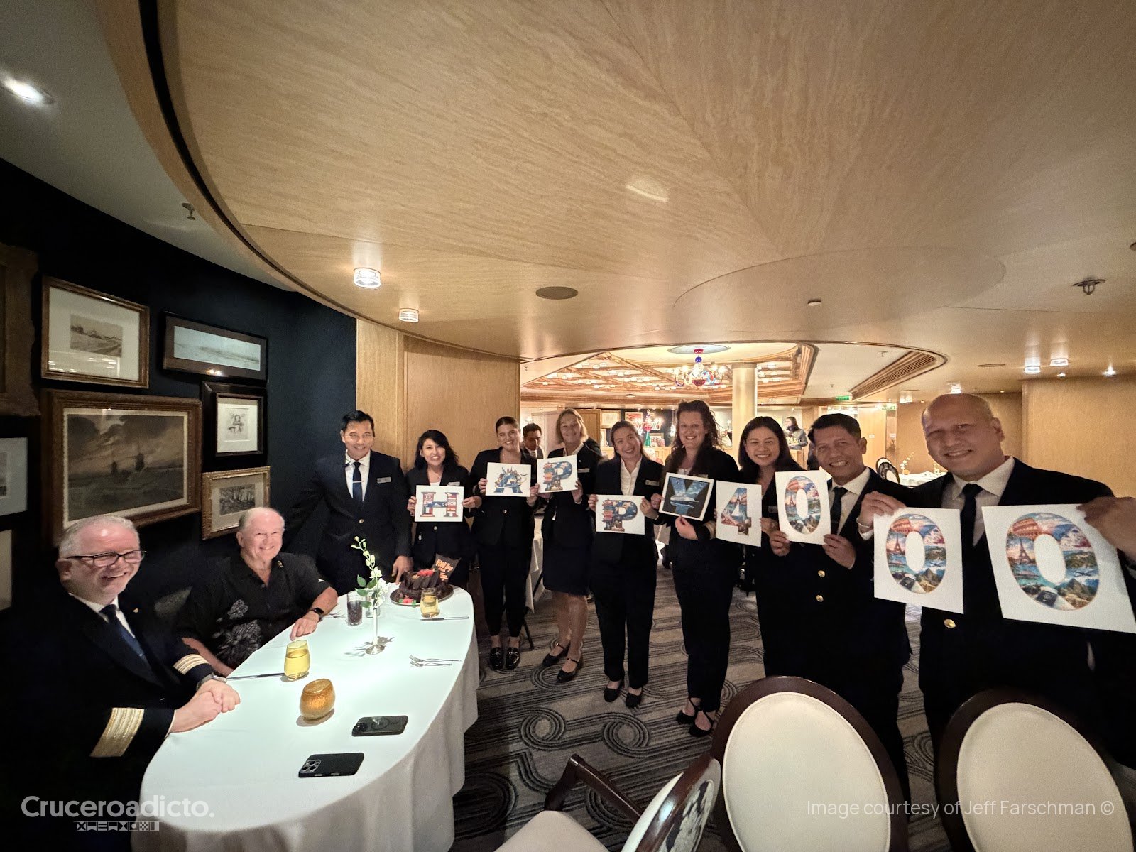 Tripulantes del ms Volendam con carteles de 4.000 días junto a la mesa de la celebración, en el comedor.