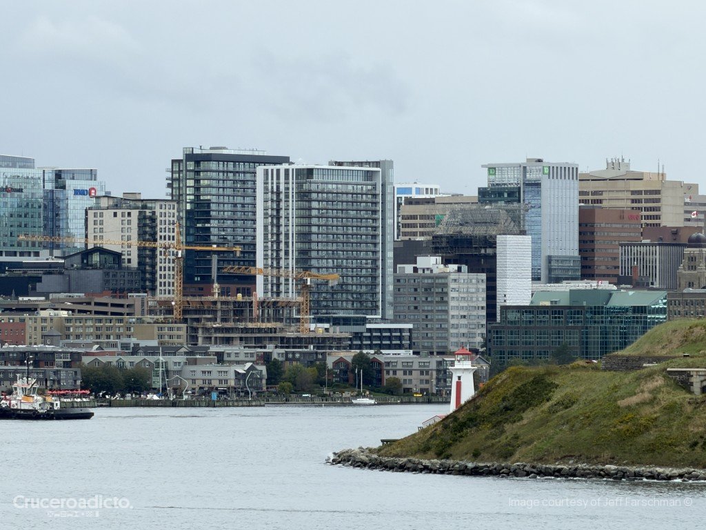 El faro de Georges Island, blanco y rojo, en el puerto de Halifax, con los edificios del centro al fondo.