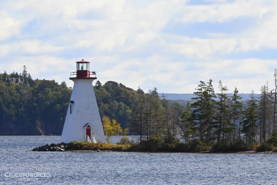 El faro de Kidston Island, blanco con linterna roja, entre abetos en el lago Bras d'Or, frente a Baddeck.