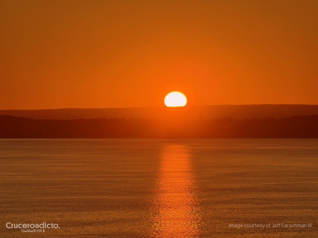 El sol bajo, junto al horizonte, tiñe de naranja el cielo y el agua del río San Lorenzo camino de Quebec.