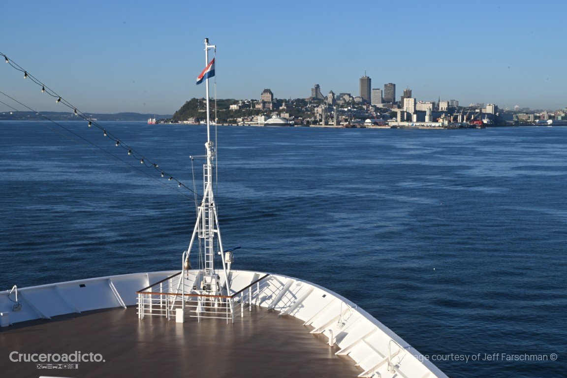 Proa del ms Volendam con la bandera neerlandesa y, al fondo, el perfil de Quebec sobre el río San Lorenzo.