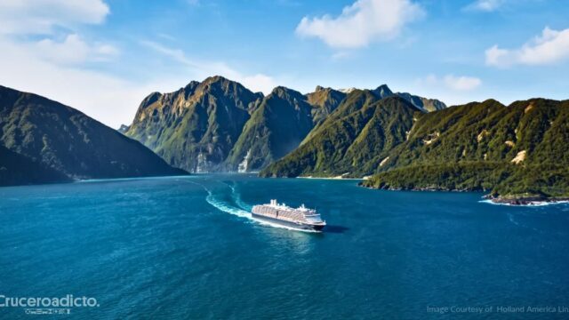 Barco de Holland America Line navegando por un fiordo entre montañas en Nueva Zelanda