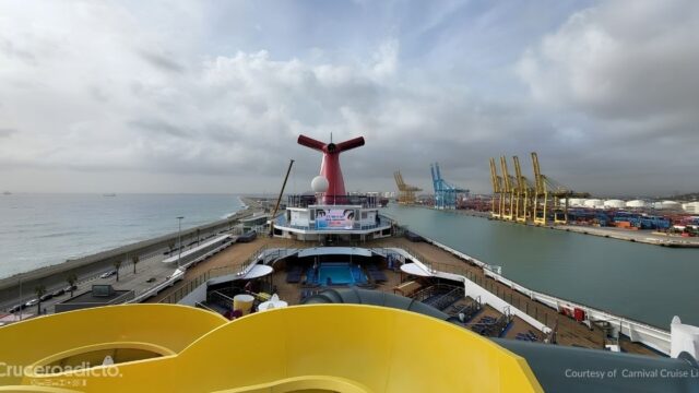 TELETIPO de noticias de Cruceros 22 Vista desde la cubierta superior del Carnival Freedom, con su chimenea de cola de ballena, frente a las grúas de un puerto