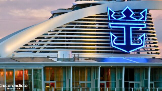 Chimenea de un barco de Royal Caribbean con el logotipo de la corona y el ancla iluminado en azul al atardecer