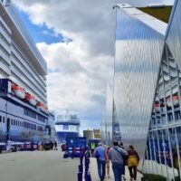 Cruceristas caminando por el muelle de cruceros de Copenhague junto a un barco de Mein Schiff y la terminal de fachada metálica