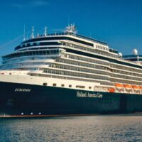 El Eurodam de Holland America Line atracado en un puerto, con su casco azul oscuro y el nombre de la naviera en el costado