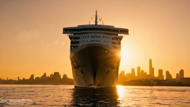 TELETIPO de noticias de Cruceros 16 El Queen Mary 2 de proa navegando al atardecer frente al perfil de rascacielos de Nueva York