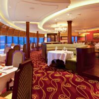 Comedor del restaurante Palo en un barco de Disney Cruise Line, con mesas junto a los ventanales sobre el mar