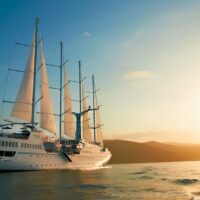 Velero de crucero de Windstar Cruises navegando con las velas desplegadas al atardecer